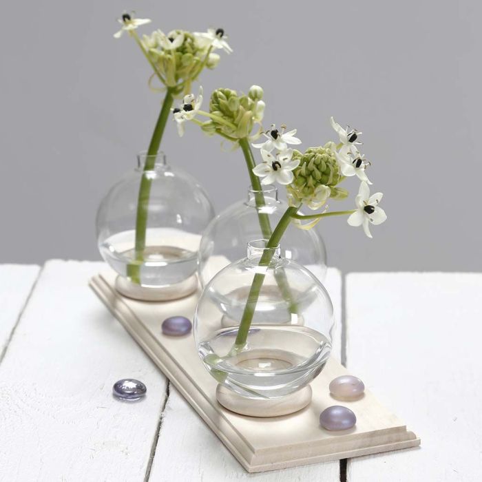 Liten vase av glasskule stående på gardinring