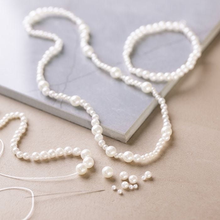 Halskjede og armbånd med hvite perlemorperler