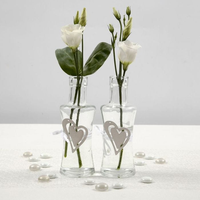 Glassvase med belte av hvitt satengbånd, isatt trehjerte