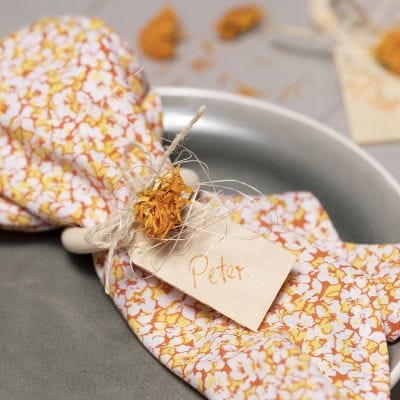 Stoffservietter av patchworkstoff med serviettring og tørkede blomster