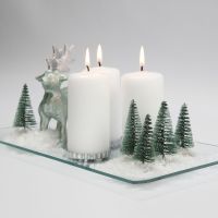 Juledekorasjon med lys, reinsdyr, trær og snø på glassfat