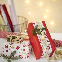 Kreativ julegaveinnpakning med to typer gavepapir og en trefigur