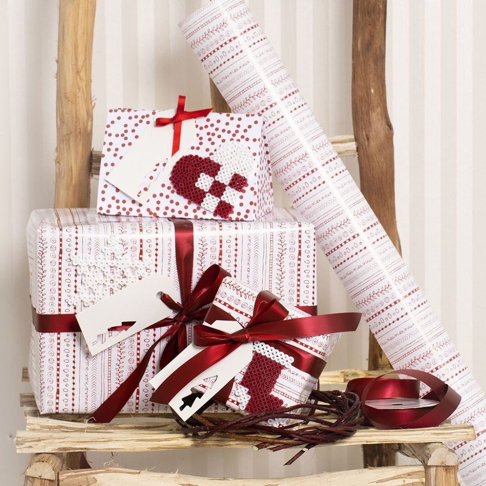 Julegaveinnpakning i rød og hvit pyntet med julemotiver i rørperler